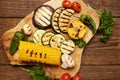 Close-up of grilled organic vegetables on a wooden cutting board on the table. Fried cornmeal, eggplant, mushrooms, tomatoes and Royalty Free Stock Photo