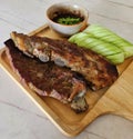 Close up Grilled pork ribs, sliced cucumber and spicy sauce on wooden tray. Royalty Free Stock Photo