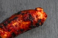 Close up of grilled sausage on small black cutting board isolated. Barbecue, grill and food concept