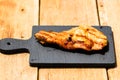 Close up of grilled steak on small black chopping board isolated. Barbecue, grill and food concept