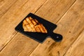 Close up of grilled steak on small black chopping board isolated. Barbecue, grill and food concept