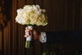 Close up of groom holding bouquet of flowers in apartment before wedding Royalty Free Stock Photo