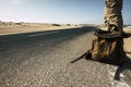 Close up ground point of view of man with leather backpack travel and wait for a car to share the trip together - sand and desert