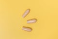 Close up group of beige rectal suppositories for anal or vaginal use on yellow background. Pills for alternative medicine