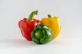 Close-up of a group of bell peppers, green, yellow and red on a white background with copy space