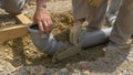 CLOSE UP: A group of builders bury a wide plastic sewage tube with concrete.