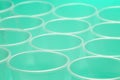 Close up of a group of empty translucent plastic cups, ordered on a turquoise colored surface