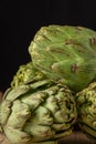 Close-up of a group of green artichokes, with selective focus, black background, vertical, Royalty Free Stock Photo