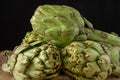 Close-up of a group of green artichokes, with selective focus, on wooden table, black background Royalty Free Stock Photo