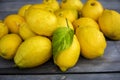 Close up of a Group of lemons with one bearing a leaf on a wood table