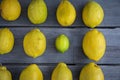Close up of a Group of lemons with one lime on a wood table