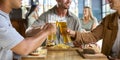 Close Up Of Group Of Male Friends Meeting Up In Bar Eating Burgers And Doing Cheers With Beer