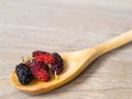 Close up group of mulberries is placed on a wooden spoon on a wooden table. Mulberry this a fruit and can be eaten it have a red a Royalty Free Stock Photo