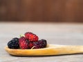 Close up group of mulberries is placed on a wooden spoon on a wooden table. Mulberry this a fruit and can be eaten it have a red Royalty Free Stock Photo