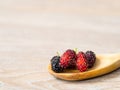 Close up group of mulberries is placed on a wooden spoon on a wooden table. Mulberry this a fruit and can be eaten it have a red a Royalty Free Stock Photo