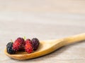 Close up group of mulberries is placed on a wooden spoon on a wooden table. Mulberry this a fruit and can be eaten it have a red a Royalty Free Stock Photo