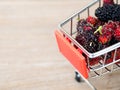 Close up group of mulberries in red shopping cart on wooden table. Mulberry this a fruit and can be eaten in have a red and purple Royalty Free Stock Photo