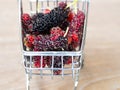 Close up group of mulberries in red shopping cart on wooden table. Mulberry this a fruit and can be eaten in have a red and purple Royalty Free Stock Photo