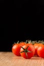 Close-up of a group of tomatoes, selective focus, on wood, black background