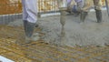 CLOSE UP: Contractors pour wet mortar over wiring while building the foundation