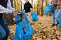 Close up of a group of volunteers collecting trash in seasonal forest at autumn