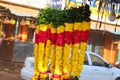 Close up of a groups of yellow marigolds flowers, red roses flowers, white jasmines flowers, and green leaves flowers chain