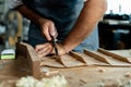 Close-up of guitar luthier using chisel to shave bracing of acoustic guitar