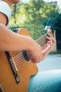 Close up guitar neck with capo in the park. Young man sitting on the bench in the park playing the guitar. Young attractive man Royalty Free Stock Photo
