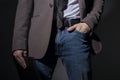 Close-up of a guy in jeans and a formal suit, holds a folder in his hand. Business style. On a dark background. Art light.