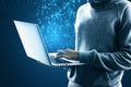 Close up of hacker using laptop with abstract glowing binary code hologram on blue background. Programming, hacking and theft Royalty Free Stock Photo