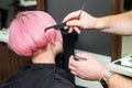 Close up of hairdresser is combing client`s pink hair in hair salon Royalty Free Stock Photo