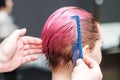 Close up of hairdresser is combing client`s wet pink hair in hair salon Royalty Free Stock Photo