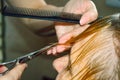 a hairdresser cuts a woman with blond short hair