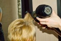 hairdresser dries hair with a hairdryer and styles