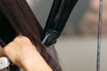 Close up of hairdressers hands drying long black hair with blow dryer and round brush. Royalty Free Stock Photo
