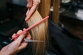 Close-up of hairstylist hands combing blonde hair before haircut in salon