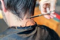 Close up of hairstylist`s hands cutting strand of man`s hair. Professional hairdresser or barber occupation.