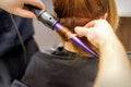 Close up of hairstylist's hands using a curling iron for hair curls in a beauty salon. Royalty Free Stock Photo