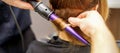 Close up of hairstylist's hands using a curling iron for hair curls in a beauty salon. Royalty Free Stock Photo