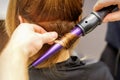 Close up of hairstylist's hands using a curling iron for hair curls in a beauty salon. Royalty Free Stock Photo