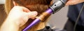 Close up of hairstylist's hands using a curling iron for hair curls in a beauty salon. Royalty Free Stock Photo