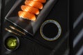 Close-up of half a black plate with salmon sushi, chopsticks, soy sauce and wasabi, black background