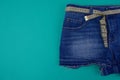 Close-up half of blue denim shorts with a centimeter instead of a belt on a blue background, next to an empty area.
