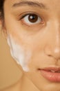 Close up half face portrait of beautiful young woman looking at camera with gentle foam facial cleanser applied on her Royalty Free Stock Photo