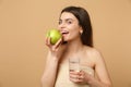 Close up half naked woman 20s with perfect skin, nude make up hold apple, water isolated on beige pastel wall background Royalty Free Stock Photo