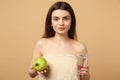 Close up half naked woman 20s with perfect skin, nude make up hold apple, water isolated on beige pastel wall background Royalty Free Stock Photo