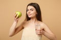 Close up half naked woman 20s with perfect skin, nude make up hold apple, water isolated on beige pastel wall background Royalty Free Stock Photo