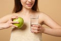 Close up half naked woman 20s with perfect skin, nude make up hold apple, water isolated on beige pastel wall background Royalty Free Stock Photo