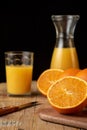 Close-up of half orange, bottle, knife, out of focus oranges on wooden table, black background Royalty Free Stock Photo