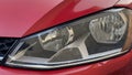 Close-up of halogen car headlights on a red car. Car details